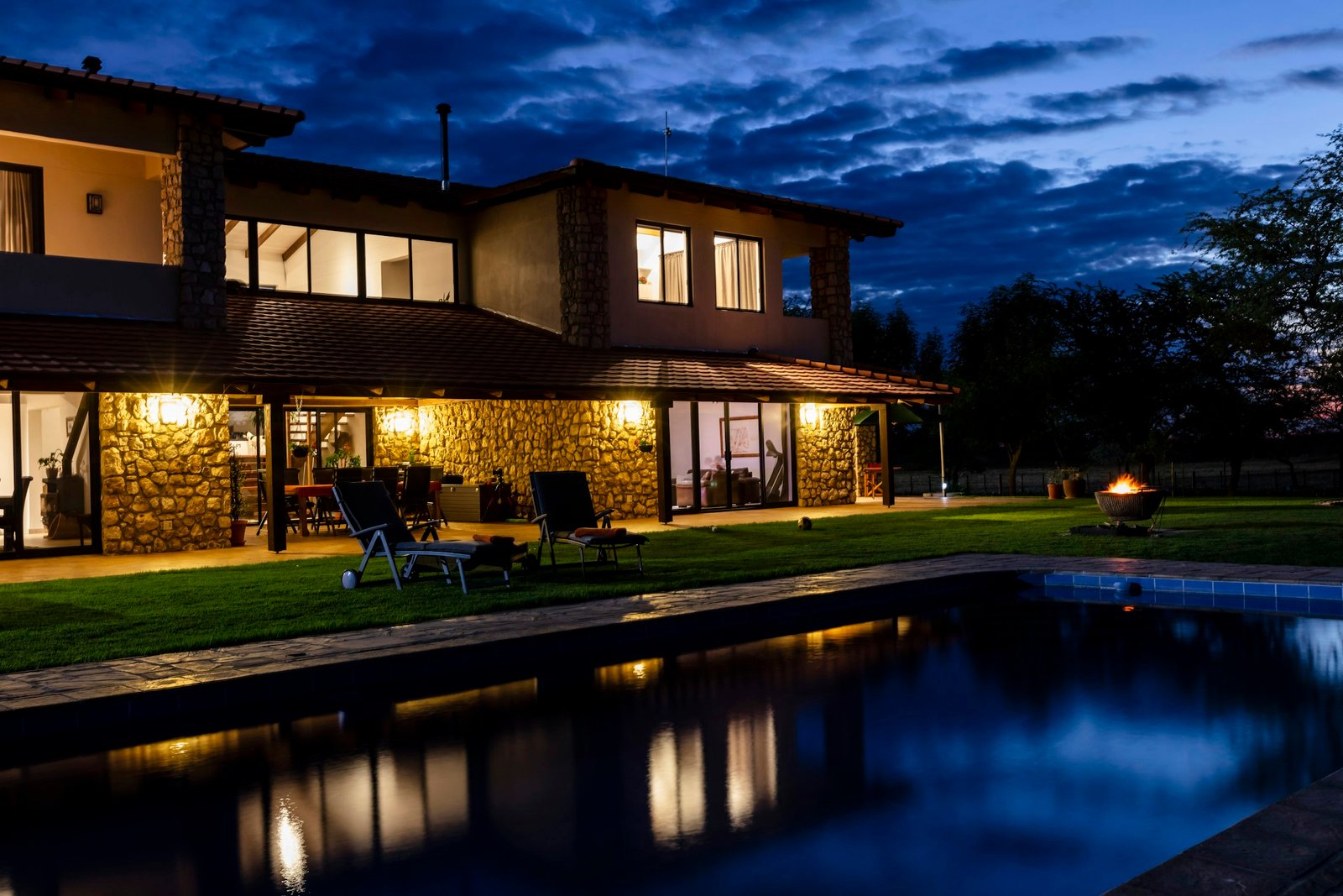Maison en pierre éclairée au crépuscule, au bord de la piscine